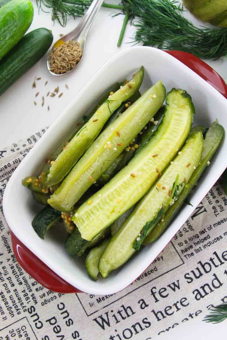 White dish with pickled cucumber spears and dill.