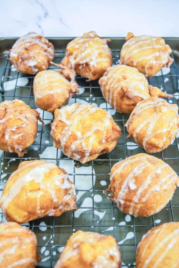 Close-up of glazed apple fritters on a cooling rack, showing golden brown texture.