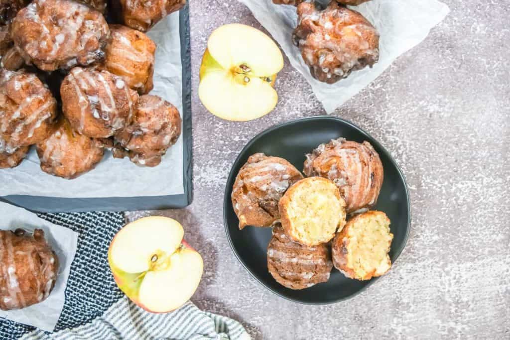Overhead view of a black plate with glazed apple fritters.