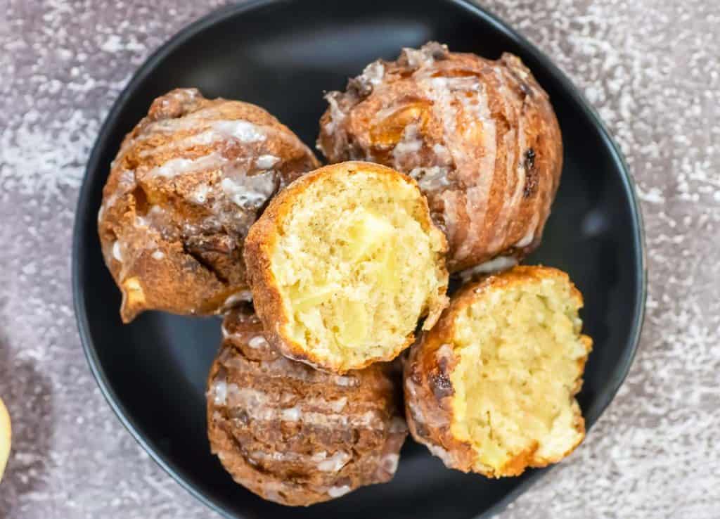 Overhead view of a black plate with glazed apple fritters.