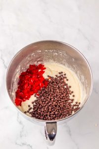 Mixing bowl with cake batter, mini chocolate chips, and chopped maraschino cherries.