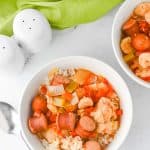 Overhead shot of two bowls of jambalaya with a crock pot and green cloth in the background.