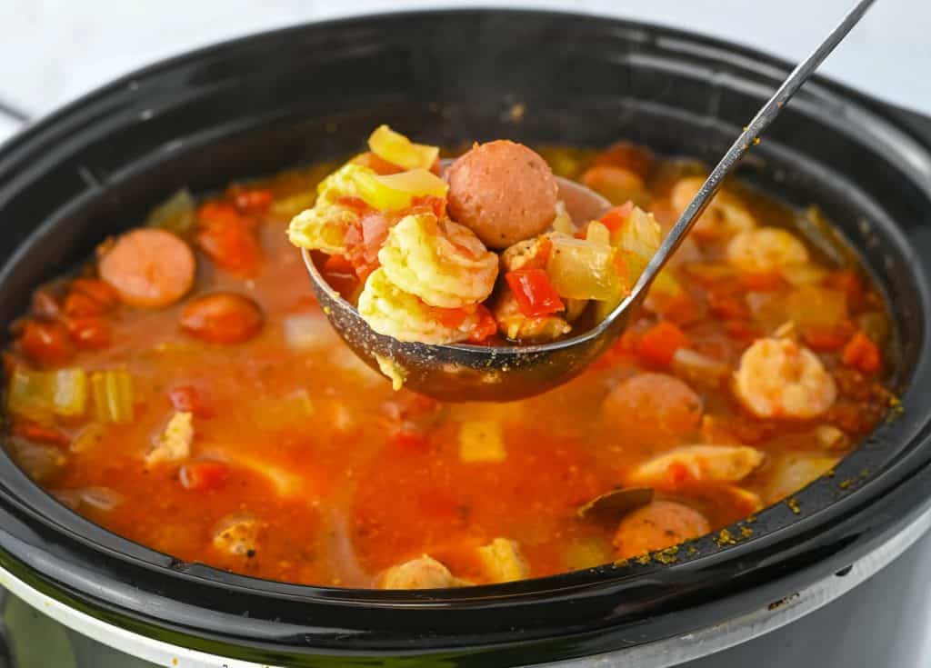 Close-up of a full ladle of jambalaya over a crock pot.