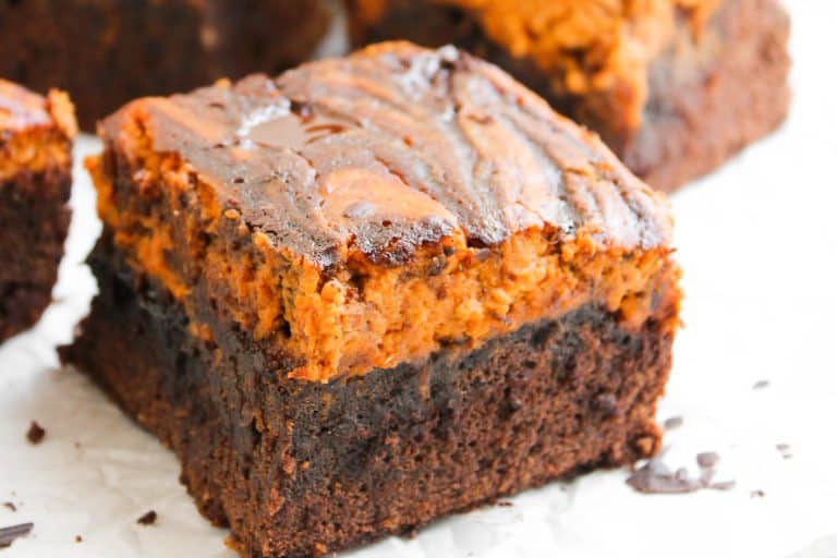 Pumpkin cheesecake brownie square with thick chocolate base and pumpkin top.