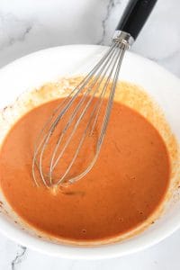 Pumpkin mixture whisked in a white bowl.