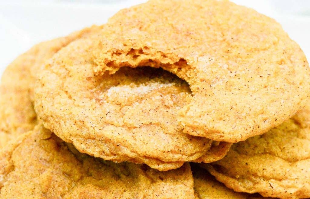 Close-up of bitten pumpkin snickerdoodle on top of cookie stack.