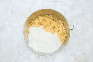 Pumpkin cookie dough with flour added in a mixing bowl.