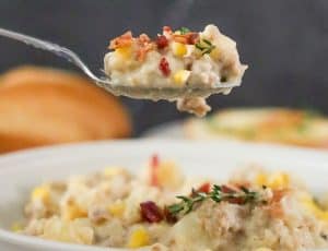 Close-up of chowder on a spoon with bacon and thyme garnish.