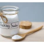 Jar of baking soda with a wooden spoon.