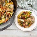 Overhead view of skillet and plate with pork chops and apples.