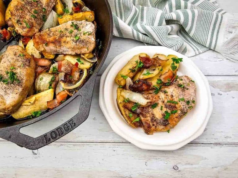 Overhead view of skillet and plate with pork chops and apples.