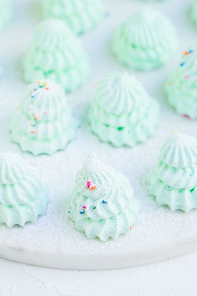 Close-up of pale green meringue trees sprinkled with sugar.