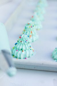 Rows of piped meringue trees with colorful sprinkles.