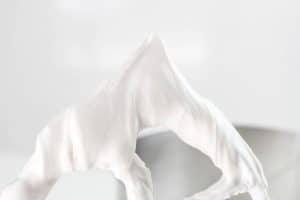 Thick royal icing clinging to a mixer paddle.