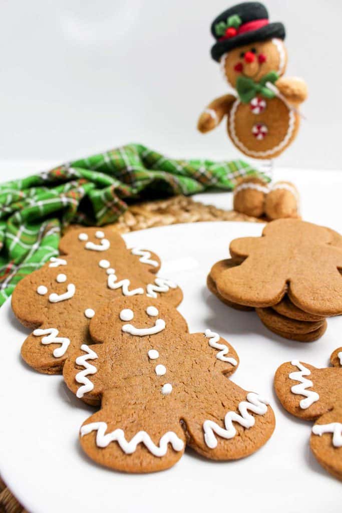 Decorated gingerbread cookies with white icing and a festive backdrop.