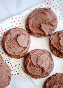 Frosted brownie cookies on parchment paper.