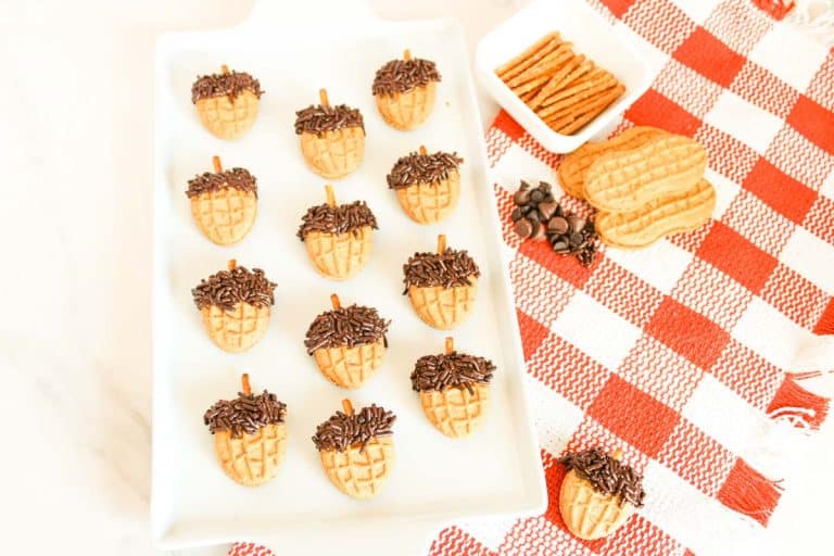 Overhead view of Nutter Butter acorns on tray with pretzels and chocolate chips nearby.