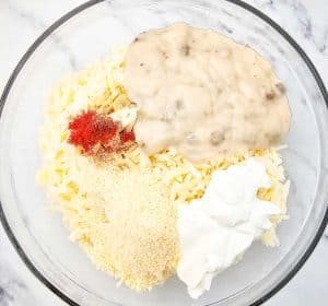 Bowl with potatoes, mushroom soup, sour cream, cheese, and seasonings.