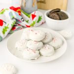 Plate of Peppermint Bark Oreos with holiday decor in the background.