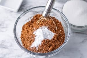 Bowl of cocoa powder and baking soda being whisked together.
