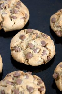 Thick baked chocolate chip cookies cooling on a pan.