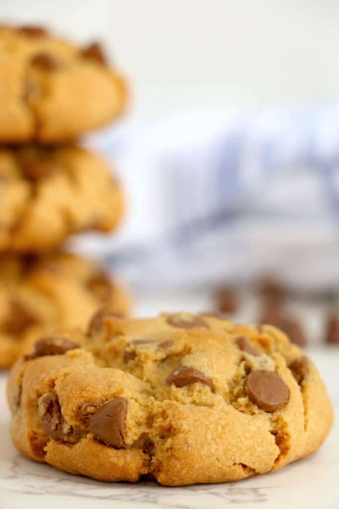 Single chocolate chip cookie on a white surface.