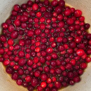 Cranberries simmering in brown sugar syrup in a pot.