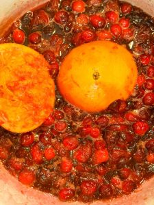 Cranberry sauce simmering with halved oranges in the pot.