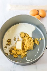 Saucepan with butter, cream, and brown sugar melting together.