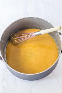 Butterscotch filling cooking in a saucepan with a whisk.