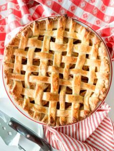 Golden lattice-top apple pie on a red-checkered cloth.