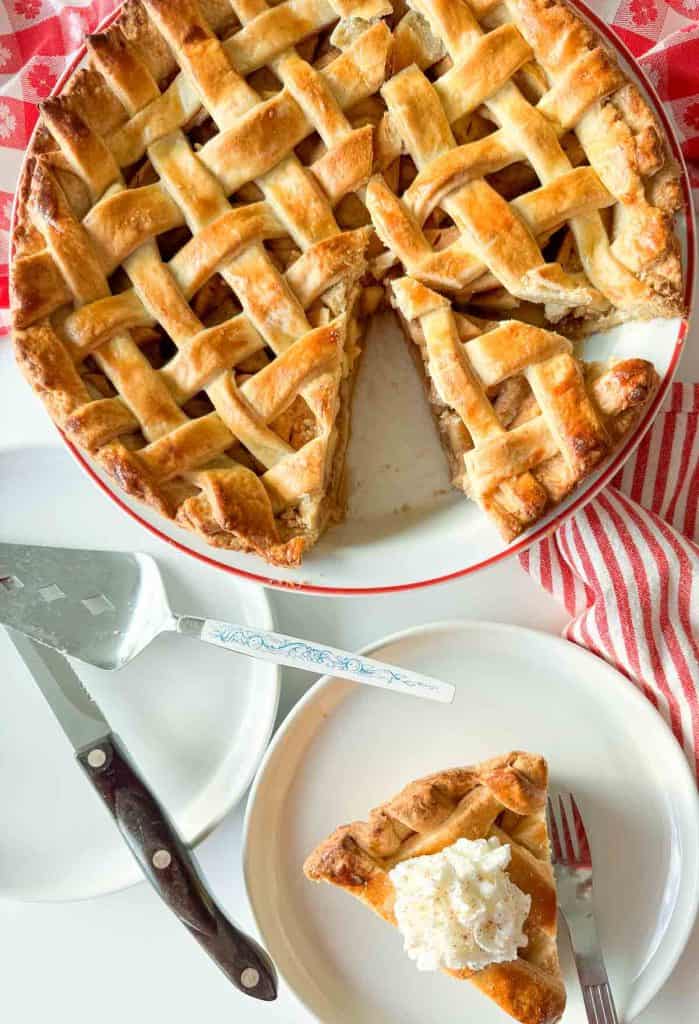Lattice apple pie with a slice removed and served on a plate.