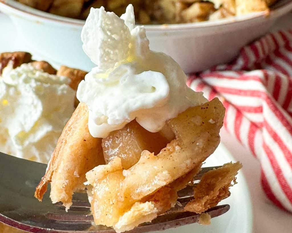 Apple pie bite topped with whipped cream against a striped towel.