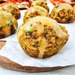 Stuffing muffins arranged on a round board, each drizzled with savory gravy.