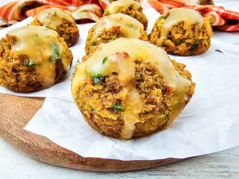 Stuffing muffins arranged on a round board, each drizzled with savory gravy.
