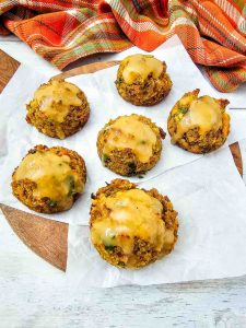 Baked stuffing muffins topped with gravy on parchment paper.