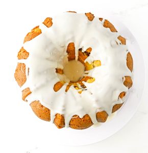 Bundt cake covered in white icing dripping down the sides.