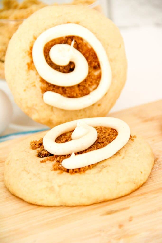 Two cinnamon swirl cookies, one propped upright behind the other to show the frosting swirl design.