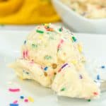 Close-up view of Funfetti edible cookie dough in a white bowl, filled with colorful sprinkles.