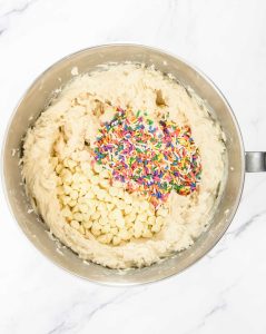 Cookie dough with white chocolate chips and rainbow sprinkles added before mixing.