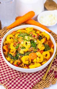 Overhead view of tortellini soup garnished with parsley and cheese.