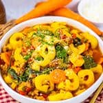 Styled food photo of tortellini soup served in a white bowl on a checkered napkin.
