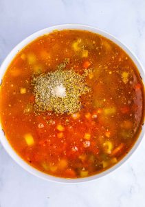 Broth poured over sausage and vegetables with herbs and seasoning on top.