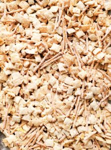 Close-up of white chocolate–coated Chex mix with pretzels and peanuts.