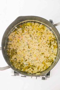 Creamy soup base with herbs cooking in a large pot.