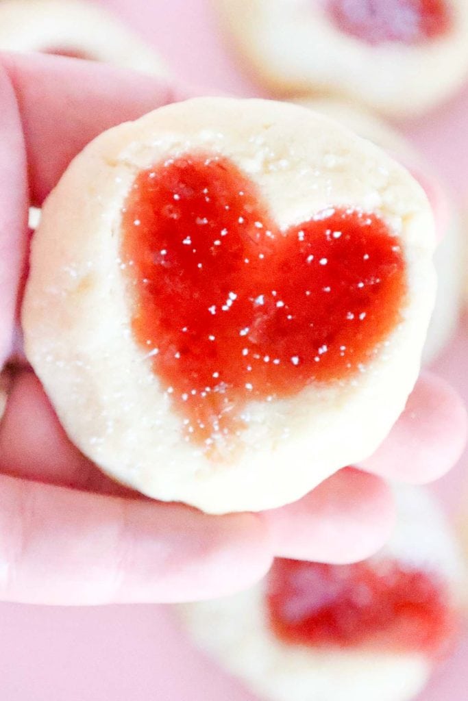 Cookie held in hand, showing heart-shaped jam center.