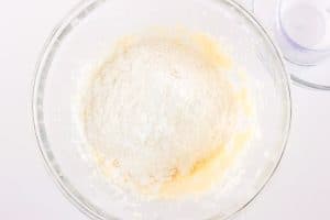 Dry ingredients, including flour, added on top of the batter in the bowl.