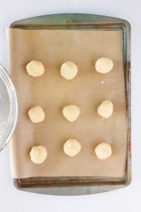 Nine dough balls spaced evenly on a parchment-lined baking sheet.