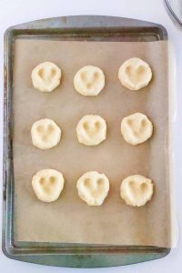 Dough balls pressed with two thumbprints, forming heart shapes.