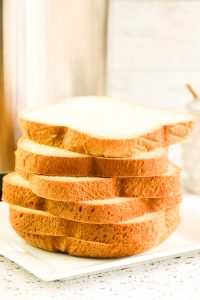 Stack of white bread slices on a white plate.